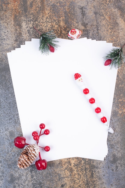 Empty sheets of paper with Christmas decoration on marble surface