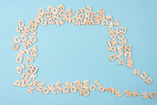 An empty speech bubble made with wooden letters on blue backdrop