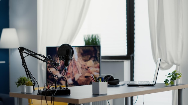 Empty streaming studio booth with modern professional audio equipment. Podcast broadcast desk having recording devices and gadgets inside office workspace with nobody in it. Studio shot