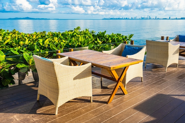 Free photo empty table and chair for dining set nearly sea ocean beach on white cloud blue sky