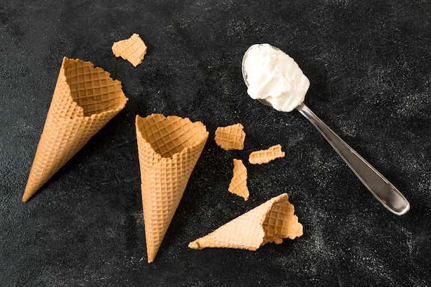 Empty waffle cones near spoon with ice cream