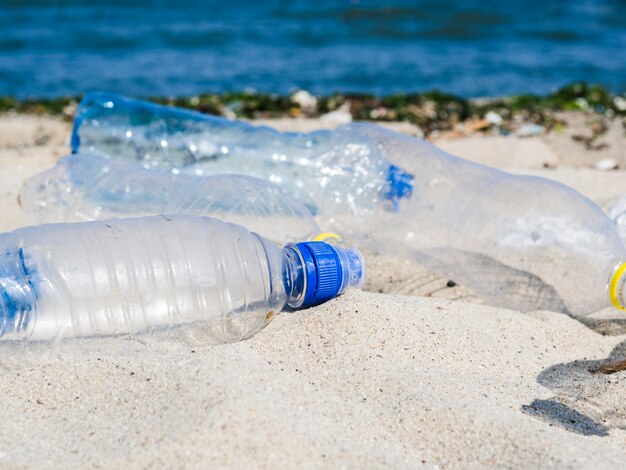 Empty waste water bottle on sand at beach