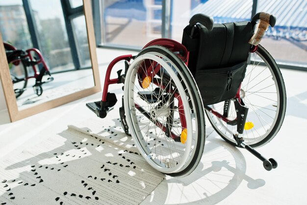 Пустая инвалидная коляска дома Инвалидная коляска в помещении в зеркале