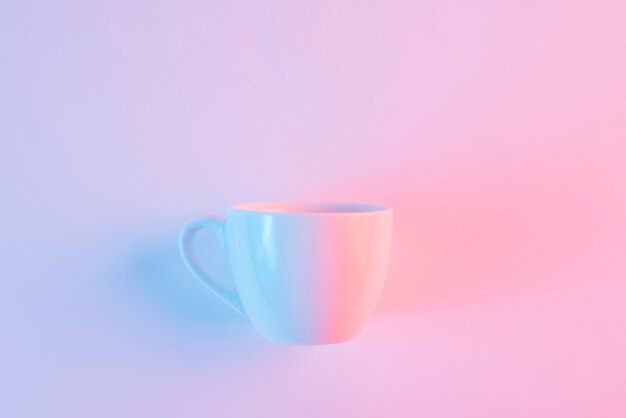An empty white ceramic cup against pink backdrop