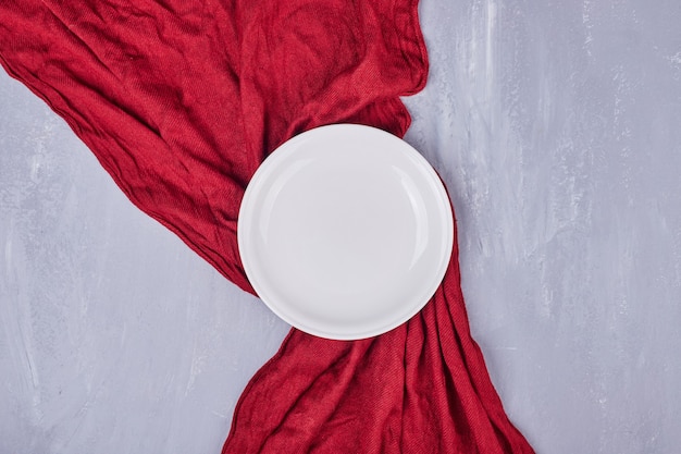 An empty white ceramic plate on the tablecloth.