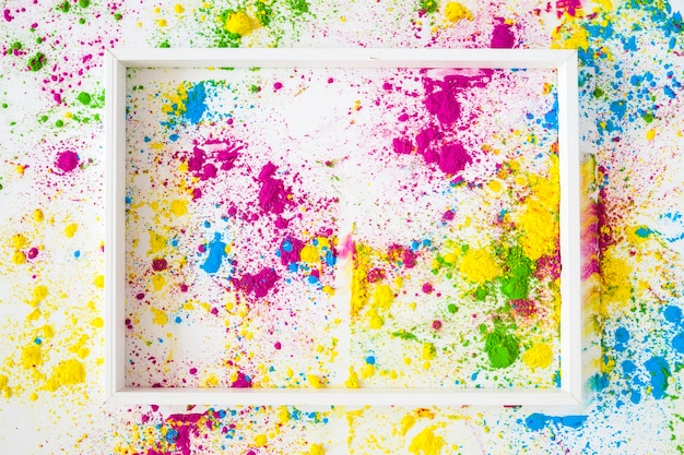 An empty white frame on colored holi powder against white background