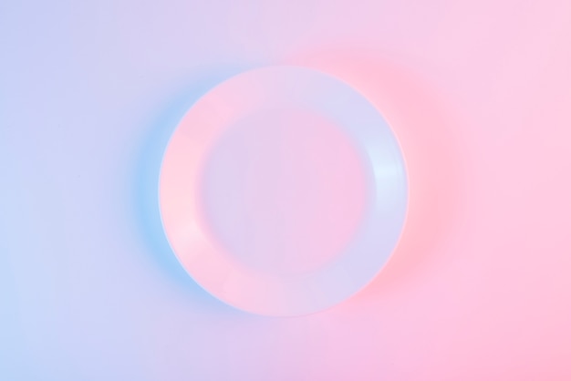 An empty white plate over colored background