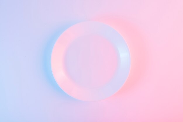 An empty white plate over colored background