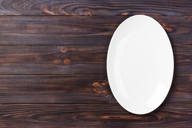 Пустая белая тарелка на деревянный стол. вид сверху