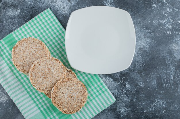 An empty white plate with crispy rice bread on a marble surface .
