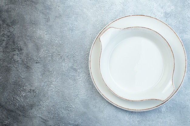 여유 공간이있는 고민 된 표면이있는 반 어두운 밝은 회색 표면의 왼쪽에 빈 흰색 수프 접시