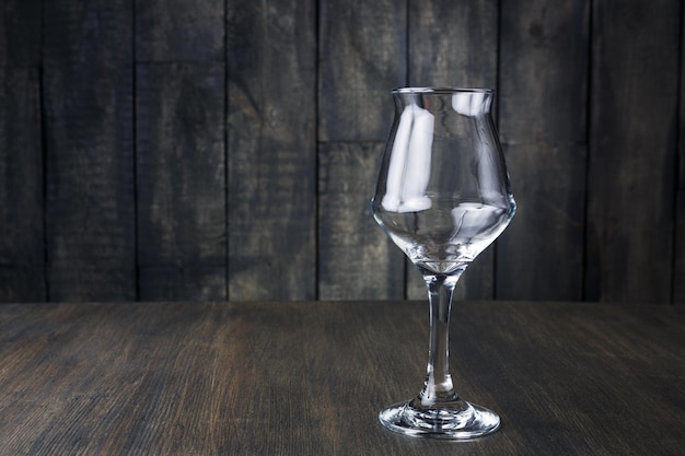 Empty wineglass on dark rustic wood background. mockup for alcohol bar menu with copy space