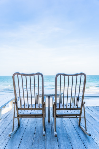 Empty wood chair and table at outdoor patio with beautiful tropical beach and sea