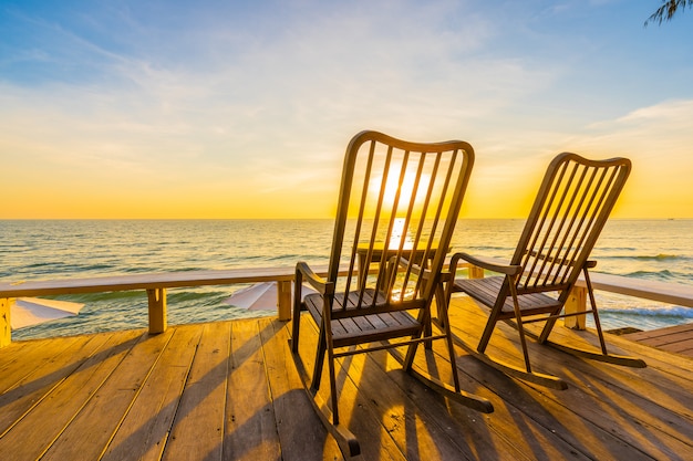 空の木製の椅子とテーブルと美しい熱帯のビーチと海の屋外パティオ