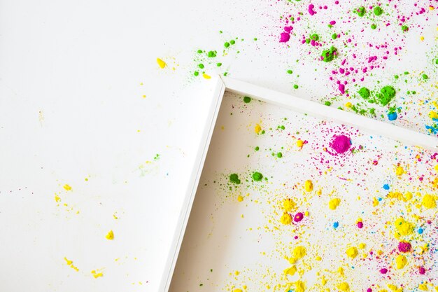 An empty wooden frame on white backgrounds with holi color powder