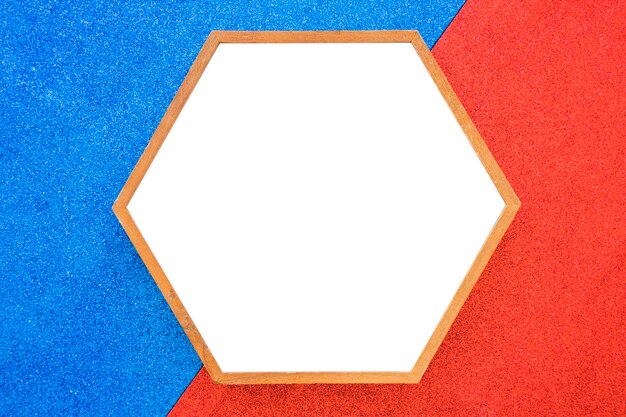 赤と青の背景に空の木製の六角形のフレーム