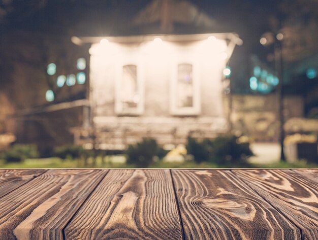 Empty wooden table in front of blurred house backdrop