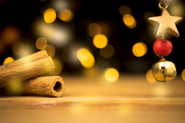 Empty wooden table with blurred christmas lights at background. wooden table with new year decoration, cinnamons and golden star close-up