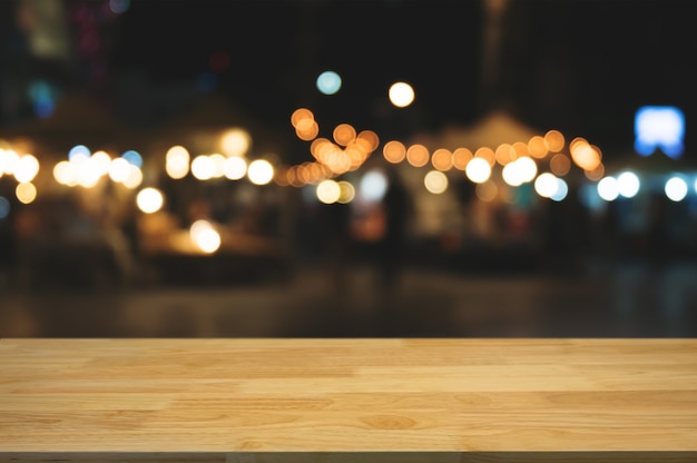 ぼんやり​と​した​夜​の​光​の​ボケ​の​背景​と​空​の​木製​の​テーブル