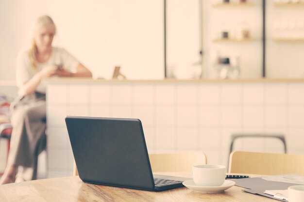 Empty workplace in co-working space. Round table with laptop, coffee cups and documents on it