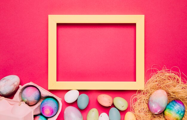 An empty yellow frame with colorful easter eggs on pink background