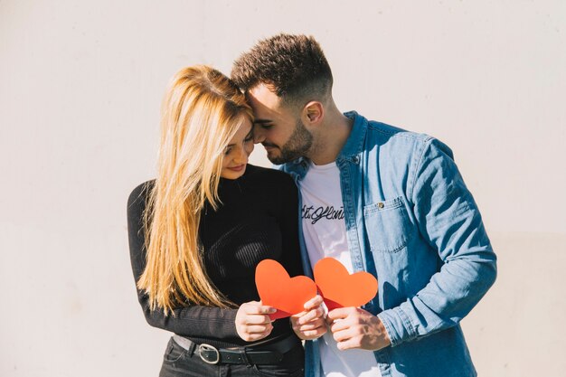 Enamored couple holding paper hearts