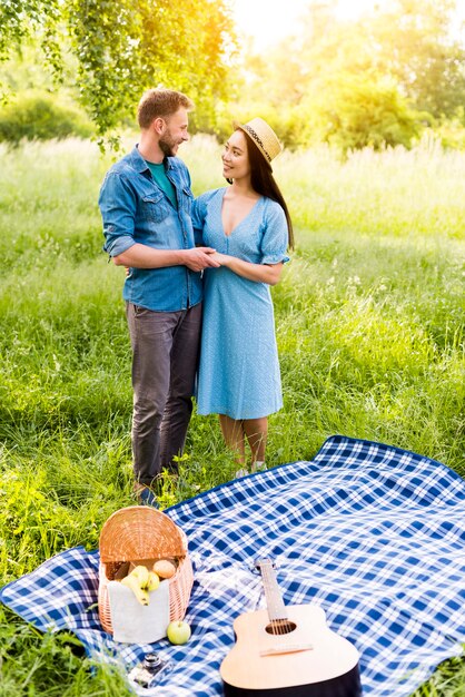 Enamored couple hugging standing by checkered plaid on picnic