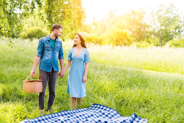 Enamored couple standing by checkered plaid holding hands in countryside