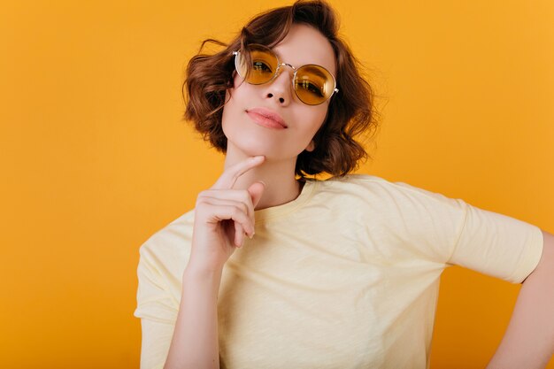 Enchanting girl with short dark hair posing with interested face expression