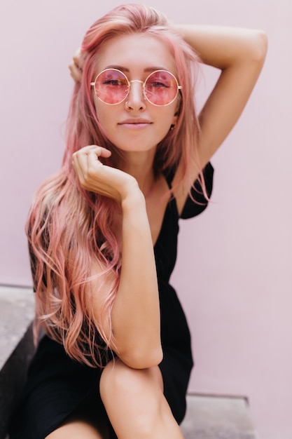 Free photo enchanting tanned woman looking to camera while posing next to white wall.