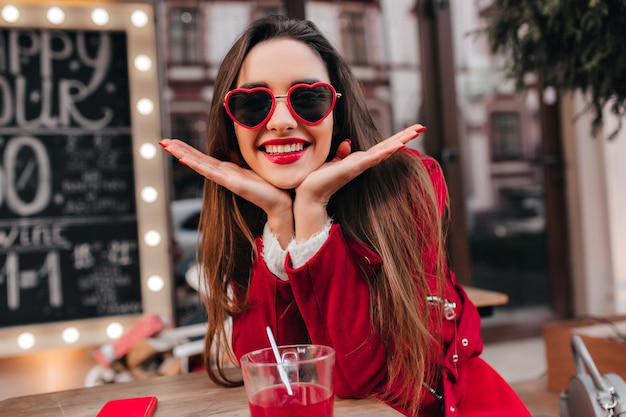 Enchanting white woman posing with pleasure in outdoor cafe