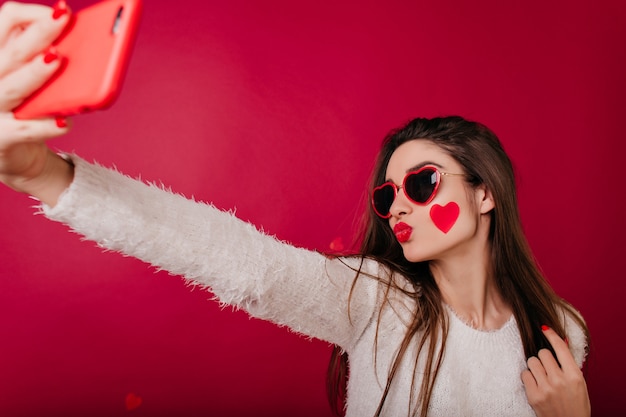 Enchanting woman with heart on cheek posing with kissing face expression