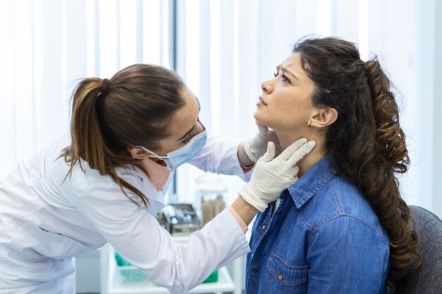 Endocrinologist examining throat of young woman in clinic Women with thyroid gland test Endocrinology hormones and treatment Inflammation of the sore throat