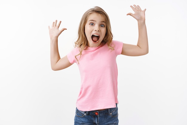 Free photo energetic cute lovely happy kid with blond hair raise hands up want scare parents screaming joyful look entertained having fun playing with school friends joyfully spend summer holidays in camp