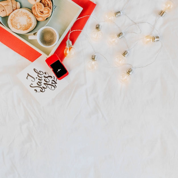 Free photo engagement ring near breakfast and light garland