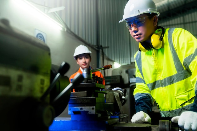 Cooperazione tra ingegneri due ingegneri della manutenzione asiatici, uomini e donne, ispezionano il sistema di protezione del relè con un dispositivo tablet per controllare il processo di controllo della qualità, lavorano in una fabbrica di produzione dell'industria pesante