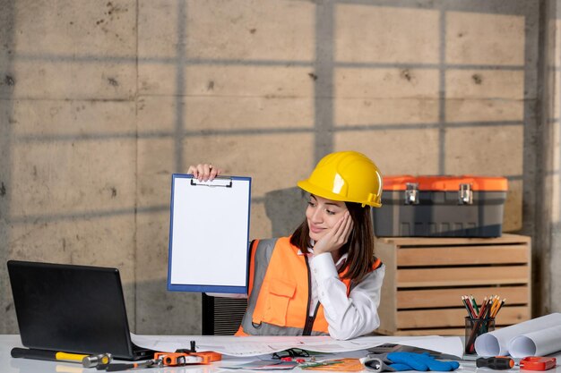 Engineer cute young smart brunette girl civil worker in helmet and vest having a new project