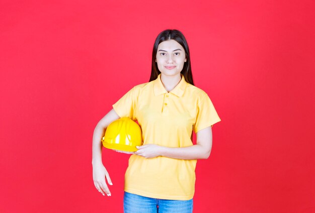 Engineer girl in yellow dresscode holding a yellow safety helmet