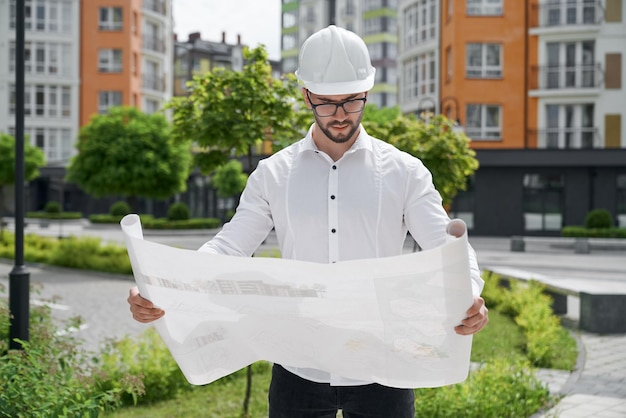 Free photo engineer in hardhat holding architectural project on paper