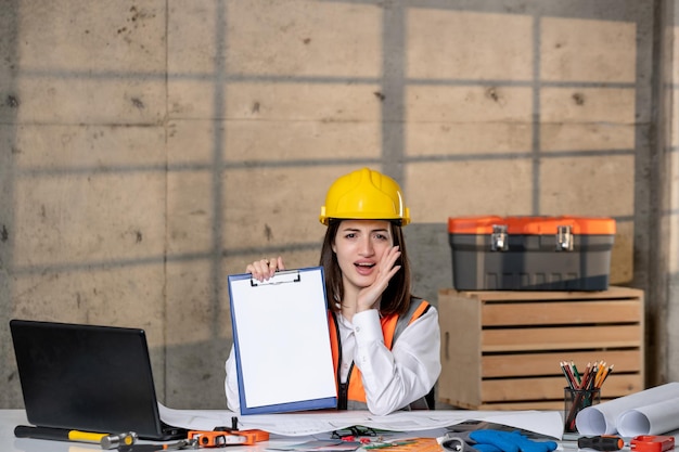 Engineer in helmet and vest civil worker smart young cute brunette girl calling for help