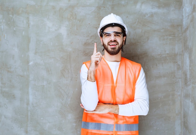 Инженер человек в белом шлеме и защитных очках держит деревянный топор.