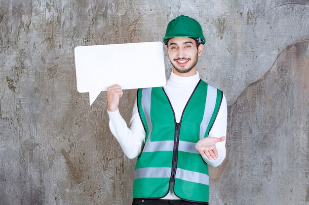 Engineer man in yellow uniform and helmet holding a blank info board