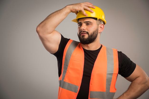 Foto gratuita ingegnere in uniforme arancione che indossa il casco giallo.