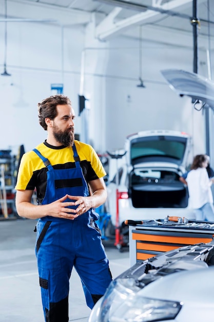 Engineer in repair shop using augmented reality holograms to check car specifications during checkup Meticulous garage employee using futuristic AR technology to examine defective vehicle