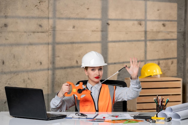 Foto gratuita ingegnere intelligente giovane ragazza bionda carina lavoratore civile in casco e giubbotto che lavora a casa