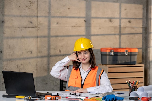 Engineer smart young cute brunette girl civil worker in helmet and vest making call sign