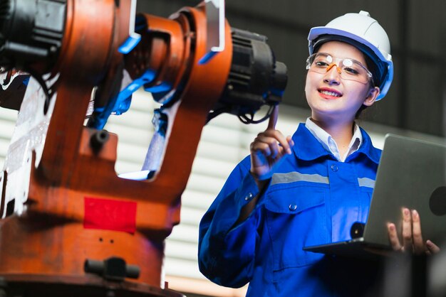 Free photo engineer specialist asian female and technician maintenance inspect relay robot arm system with laptop to control quality operate process work heavy industry 40 manufacturing smart factory