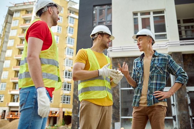 Free photo engineer and two workers communicating at construction site