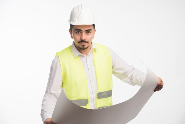 Engineer in uniform holding architectural plan of the construction.