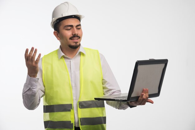 Engineer in uniform holding a laptop and talking. 